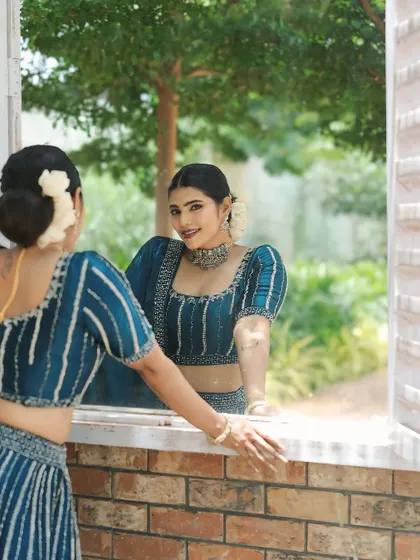 A creative reflection shot. The makeup looks flawless from every angle, highlighting her best features.
