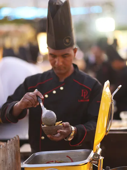 A chef assembles a Burrito Rice Bowl, carefully layering ingredients in a natural coconut shell. This showcases our commitment to unique presentation and fresh, flavourful food.