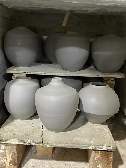 A shelf full of freshly thrown pots, waiting to dry. Each one has a slightly different curve and character. This is the quiet stage before they get trimmed and fired.