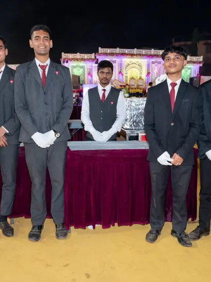 My professional service staff standing ready at their station during a large wedding event in Panvel. They are in full uniform, including gloves, to ensure hygiene and professional service.