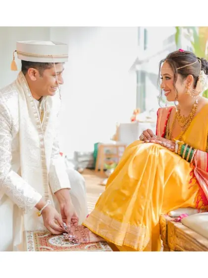 A traditional Marathi wedding ritual where the groom adorns the bride's feet. The gentle act and their shared smile make this a beautiful and meaningful photograph.