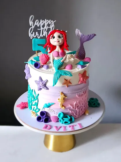 The full view of the mermaid cake, showcasing the beautiful color gradient on the buttercream and the arrangement of all the handcrafted sea-themed toppers.