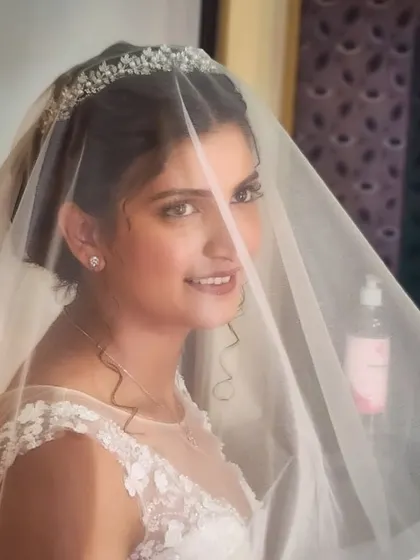 A peek through the veil. This bride's soft makeup and gentle smile create a look of ethereal beauty.
