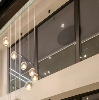 The cascading glass orb chandelier, a signature feature in our multi-level designs, creating a sense of vertical connection and elegance.