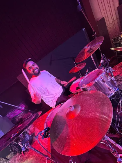 Our drummer, smiling behind the kit. There's no "I" in this team, just a shared passion for music.