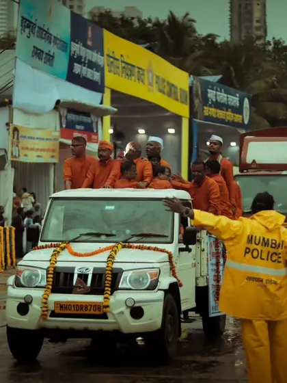 A Mumbai police officer manages the traffic during the Ganesh procession, a crucial part of the festival's organization. The shot captures a moment of order amidst the joyful chaos.