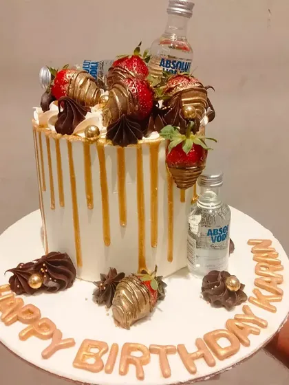 A fun and boozy cake for a birthday celebration. This drip cake is decorated with chocolate-covered strawberries and miniature bottles of Absolut Vodka.