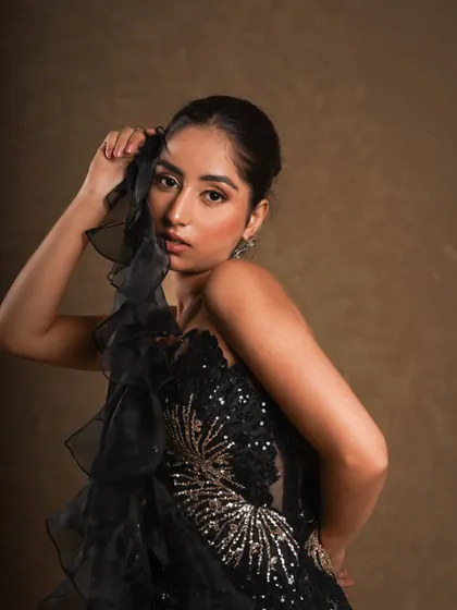 A close-up portrait focusing on the delicate, ruffled organza sleeve and the detailed bodice. This highlights the modern, glamorous elements of the Indo-Western fusion piece.