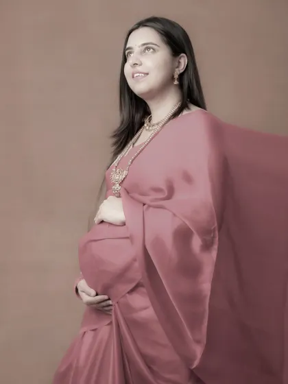 A hopeful and serene portrait of a mom-to-be in a dusty pink saree. The soft, flowing fabric and her upward gaze give this image a dreamy and artistic quality.