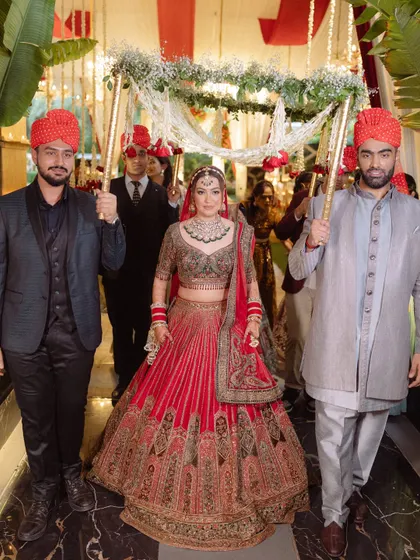 The bride makes her grand entrance under a beautiful 'phoolon ki chadar' held by her brothers, a classic and heartwarming Sikh wedding tradition.