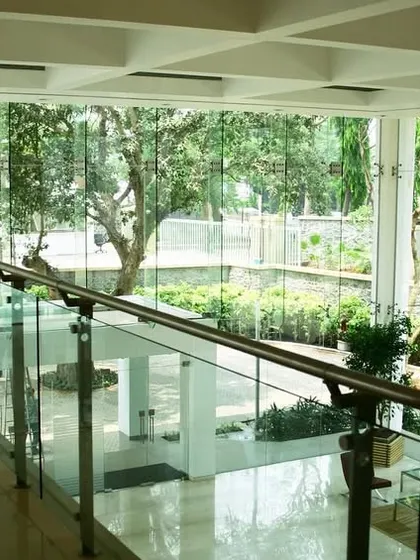 The interior of TCS Yantra Park, where glass railings and open corridors maintain visual connectivity across different levels and to the outdoor courtyards. The design prioritizes transparency and a sense of openness.