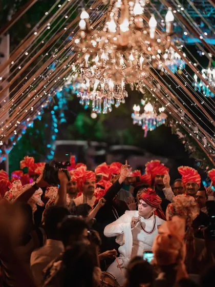 The groom's Baraat, a vibrant procession of dance and music. I captured the energy from within the crowd, showing the groom dancing under a canopy of lights and turbans.