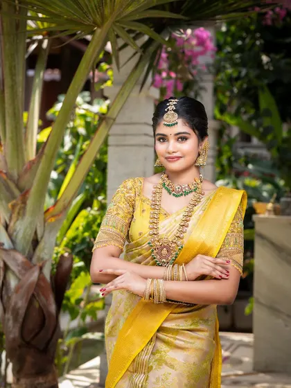 A model looking radiant in a yellow saree, complemented by a traditional Kempu and green stone jewellery set.