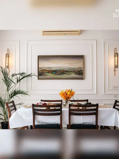 A symmetrical view of the classic contemporary dining room. The artwork is perfectly centered between two elegant wall sconces, creating a balanced and harmonious composition that reflects refined taste.