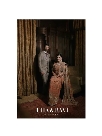 An editorial portrait of Uha and Ravi in Hyderabad. The rich, dark wood and classic furniture of the Taj Falaknuma add a layer of vintage sophistication.