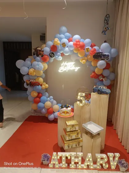 A fun Cars-themed birthday party setup. The circular balloon arch with character cutouts and a neon sign is perfect for any little racing fan.