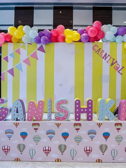 A personalized name display for "Ganishka" at her carnival party. The vibrant letters, hot-air-balloon-themed table skirt, and striped backdrop create a cheerful and custom photo spot.