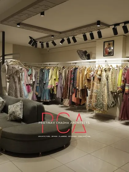 The main showroom floor of the Jubinav Chadha studio, showing the arrangement of clothing racks and the central curved sofa for clients.