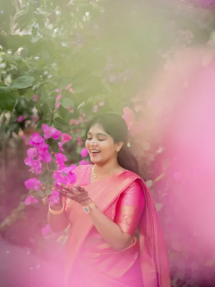 A dreamy and artistic portrait of the bride-to-be, surrounded by pink flowers that match her saree.
