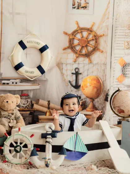 Ahoy, little sailor! This nautical-themed shoot is perfect for an adventurous baby, featuring a boat, a ship's wheel, and a classic sailor outfit.