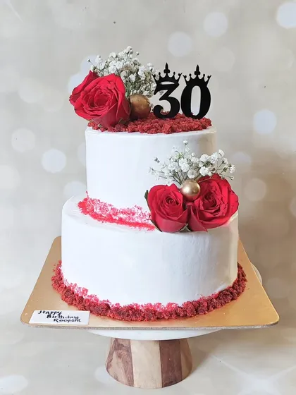 A different view of the two-tier red velvet and white ganache cake, showcasing the fresh roses and "30" topper. This design is versatile enough for milestone birthdays, anniversaries, or small weddings.