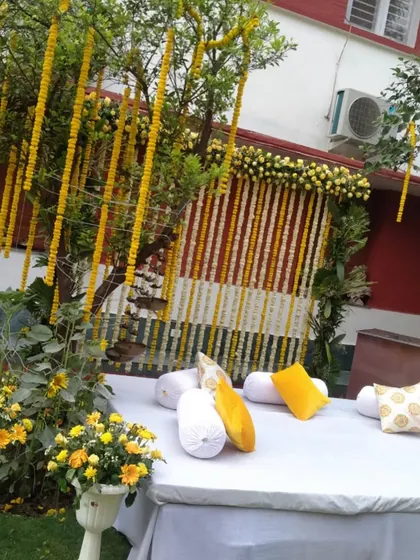 This outdoor setup shows how I use natural elements, like decorating a tree with marigold strings, to blend the decor with the surroundings for a beautiful Haldi function.