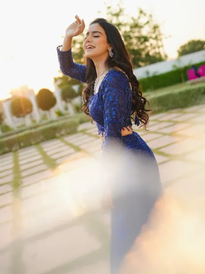 A joyful, candid shot with a lens flare effect, adding a touch of magic to this sparkling blue outfit.