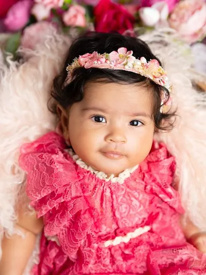A sweet and calm portrait of a baby girl nestled in a bowl of flowers. The rich pink colors make this a vibrant and beautiful photo.