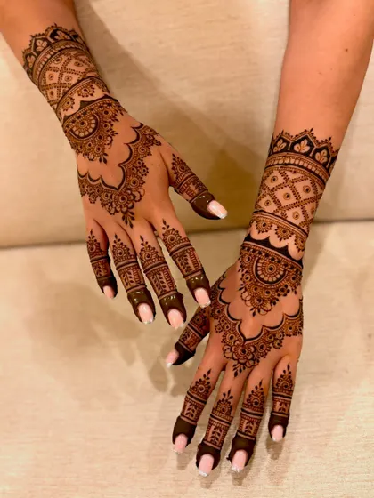 An angled view of a dense engagement mehendi, showing the layers of patterns on the wrist and fingers.