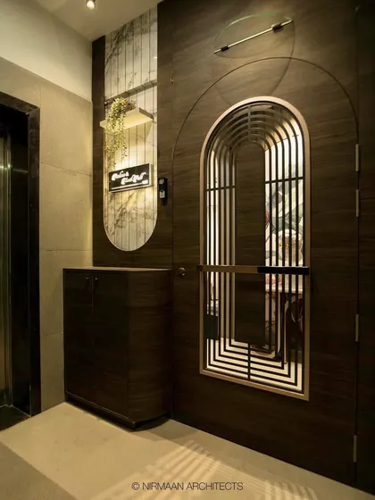 The entrance and foyer of the Sushil Advait residence, featuring an arched safety door and tropical wallpaper. We believe in making every part of the home, including the entrance, a design statement.