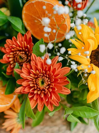 Another beautiful centerpiece, combining the bright yellows of sunflowers with the deep orange of chrysanthemums and fresh citrus accents.