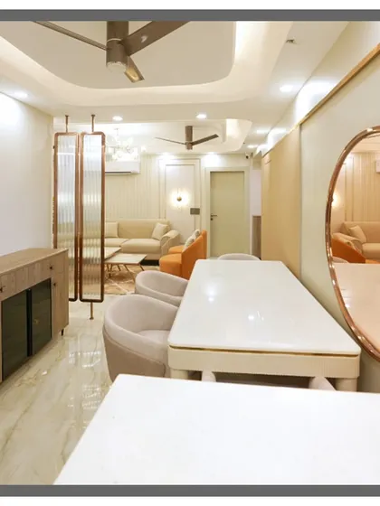 A view from the dining table looking towards the living area, showing the open and connected feel of the space. The rose-gold screen partition adds a decorative touch.
