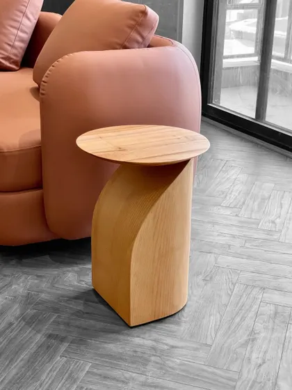 The details are where the soul of your home is found. This custom side table, with its unique curved form crafted from solid wood, adds a touch of minimal elegance next to a sofa.