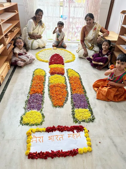The children's excitement is clear as they gather around the intricate flower arrangement during our Onam festival activities.