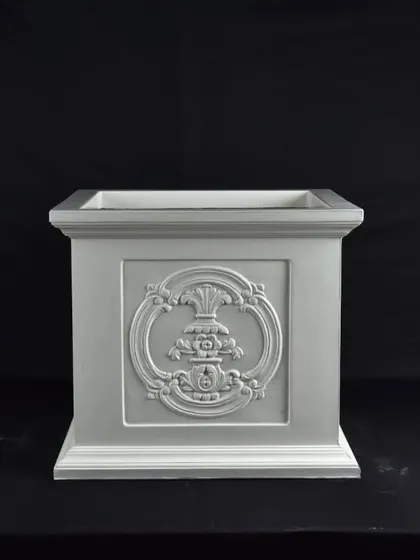 An ornate, square fiber planter with a decorative emblem. This type of pot is ideal for traditional or classic garden designs.