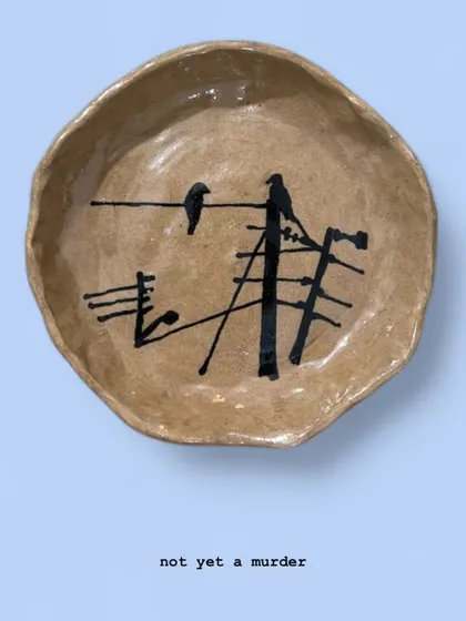 'Not Yet a Murder' is a small, hand-formed bowl depicting a common Mumbai scene: two crows on a tangle of wires. It’s a piece of urban-inspired pottery that finds beauty in the everyday chaos.