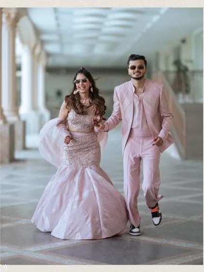 A fun and energetic shot of the couple running towards the camera, hand in hand. Their matching pink outfits and sunglasses perfectly suit the lively, carnival theme of their outdoor event.