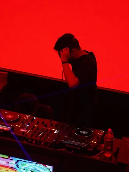 A moment of concentration at the decks against a stark red background. DJing is not just about playing music, it's about feeling it.