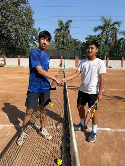 Two young players shaking hands over the net. Our internal tournaments provide a safe and supportive environment to experience competitive play.