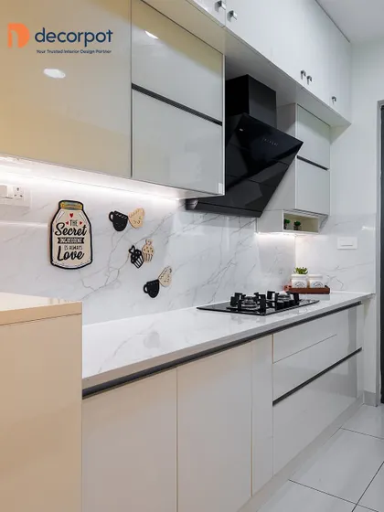 This parallel kitchen features sleek, handleless cabinets in a light cream color. The marble-patterned backsplash and under-cabinet lighting create a bright and luxurious feel, proving that simple designs can be incredibly elegant.