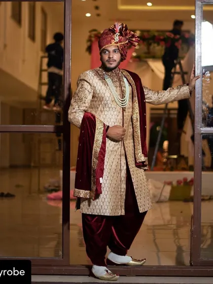 One of our clients looking absolutely regal on his wedding day. He is wearing a golden brocade sherwani paired with a maroon dhoti, velvet stole, and a matching safa.