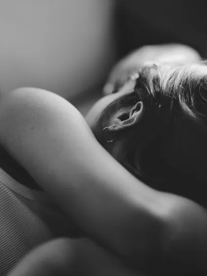 A close-up, artistic black and white shot focusing on the back of a person's neck and ear as they rest. This intimate and abstract composition evokes a sense of peace and vulnerability.