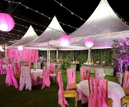 The guest seating area for the birthday party, with pink chair covers and tents illuminated by paper lanterns.