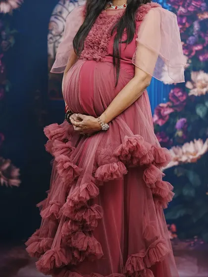 This pastel onion pink gown is made from a soft, flowy net that is comfortable and looks beautiful. I also provide matching jewellery on rent to complete your maternity photoshoot look.