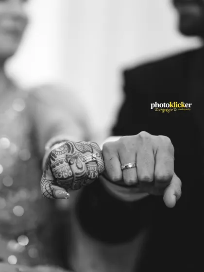A symbolic black and white shot of the couple's fists together, showcasing their wedding rings and the bride's intricate henna design.