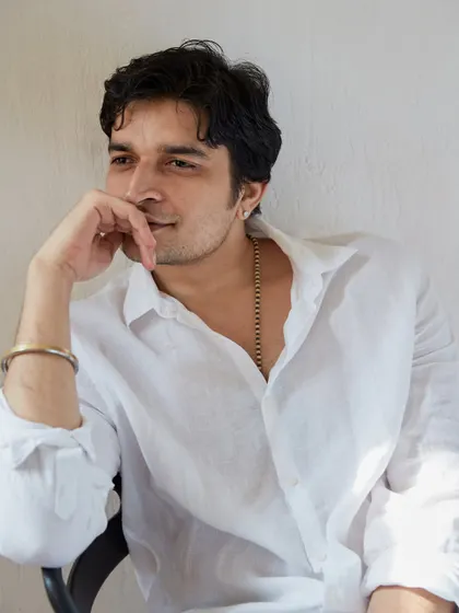 A candid, relaxed moment captured during a portrait session. The natural light from the window and the simple white shirt create a fresh and honest feel.