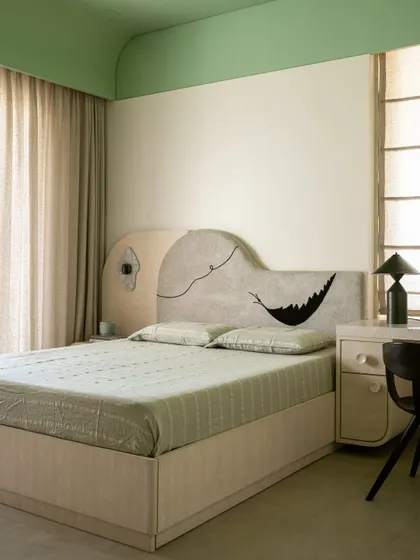 This bedroom in Soft Serve features a whimsical, hand-doodled headboard, adding a touch of personality to the calm, mint-and-beige color scheme.