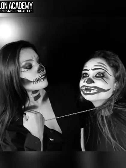 A black and white photo of two students with skull and clown Halloween makeup, highlighting the strong contrast and line work achieved through our training.