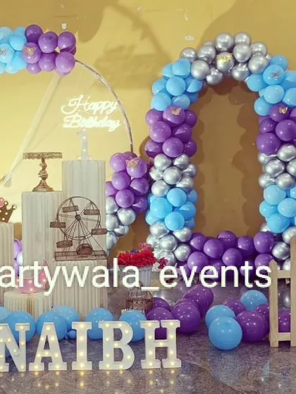 A unique "60" shaped balloon arch for a 60th birthday celebration. The purple, blue, and silver colors are modern and celebratory.