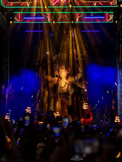 A combination of warm spotlights and cool background lighting creates depth and focus. This photo shows how I balance different lighting elements to highlight the Ganpati idol while illuminating the entire procession route for the crowd.